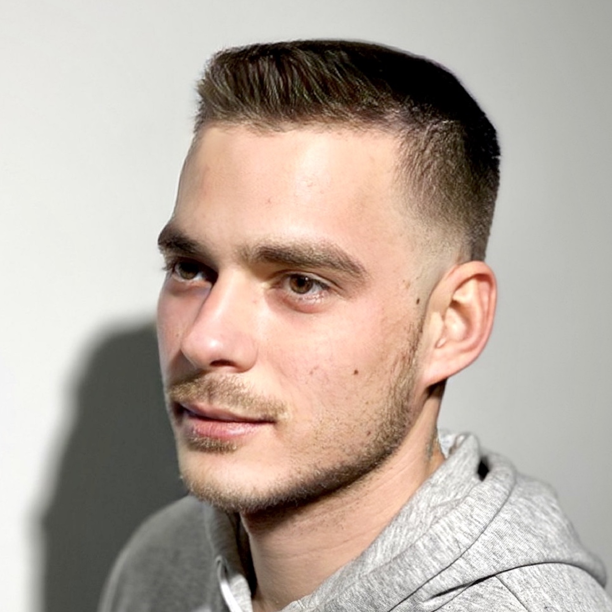 Modern fade férfi frizura hosszabb felső résszel és borotvált oldalakkal.